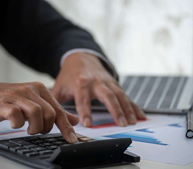 Close-up of hands calculating duty and tax figures alongside financial documents